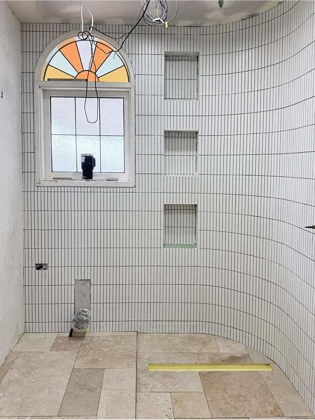 Complex bathroom tiling job with arch window and recessed shelving